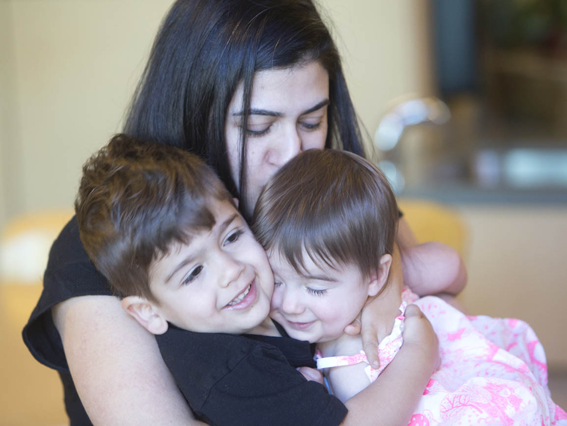 Two children being hugged by their mother