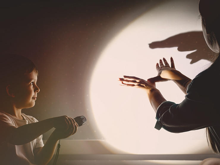 Kids using light to make shadow puppets on the wall at day care 