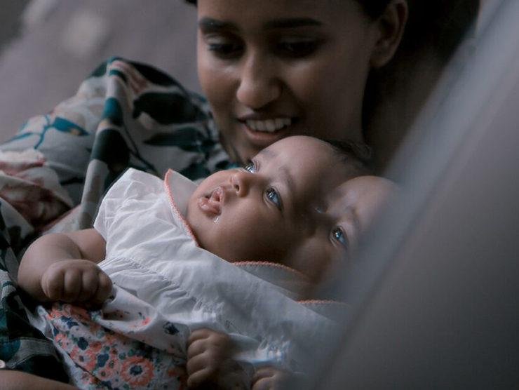 Baby being held by mother in front of a mirror 