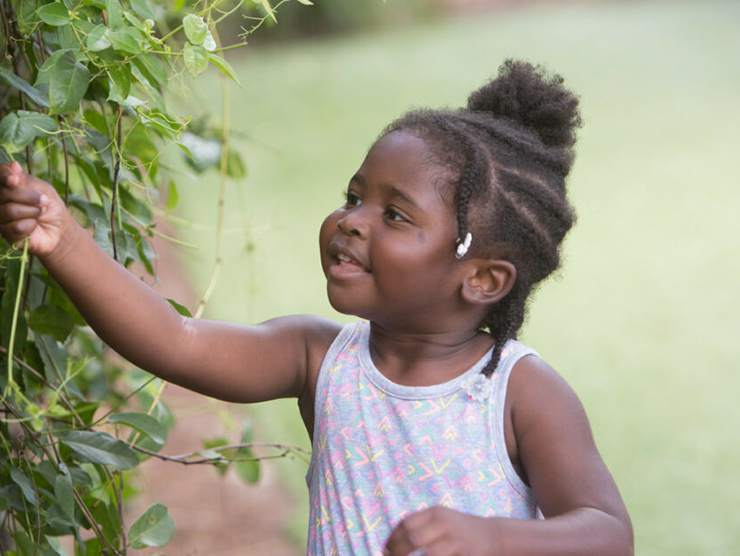 Toddler playing with vines and leaves outside of day care 