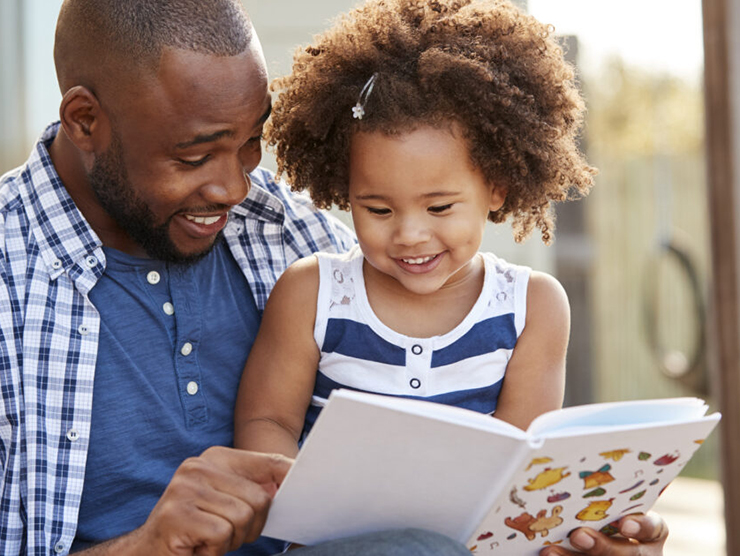 Father and daughter reading a book and laughing together 