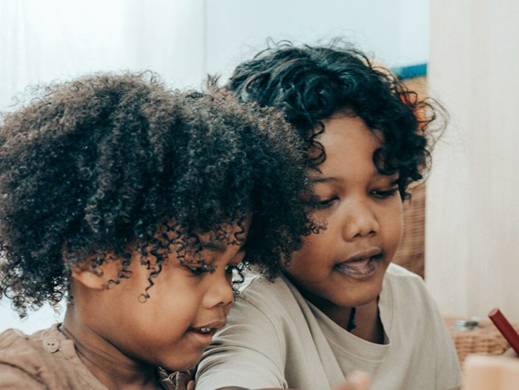 Two children drawing their self portraits at home  