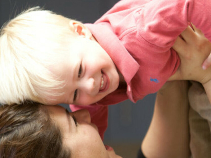 Adult holding toddler while laughing at day care