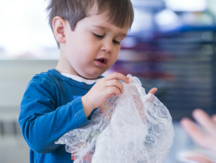 Toddler playing with textured cloth at Bright Horizons day care 