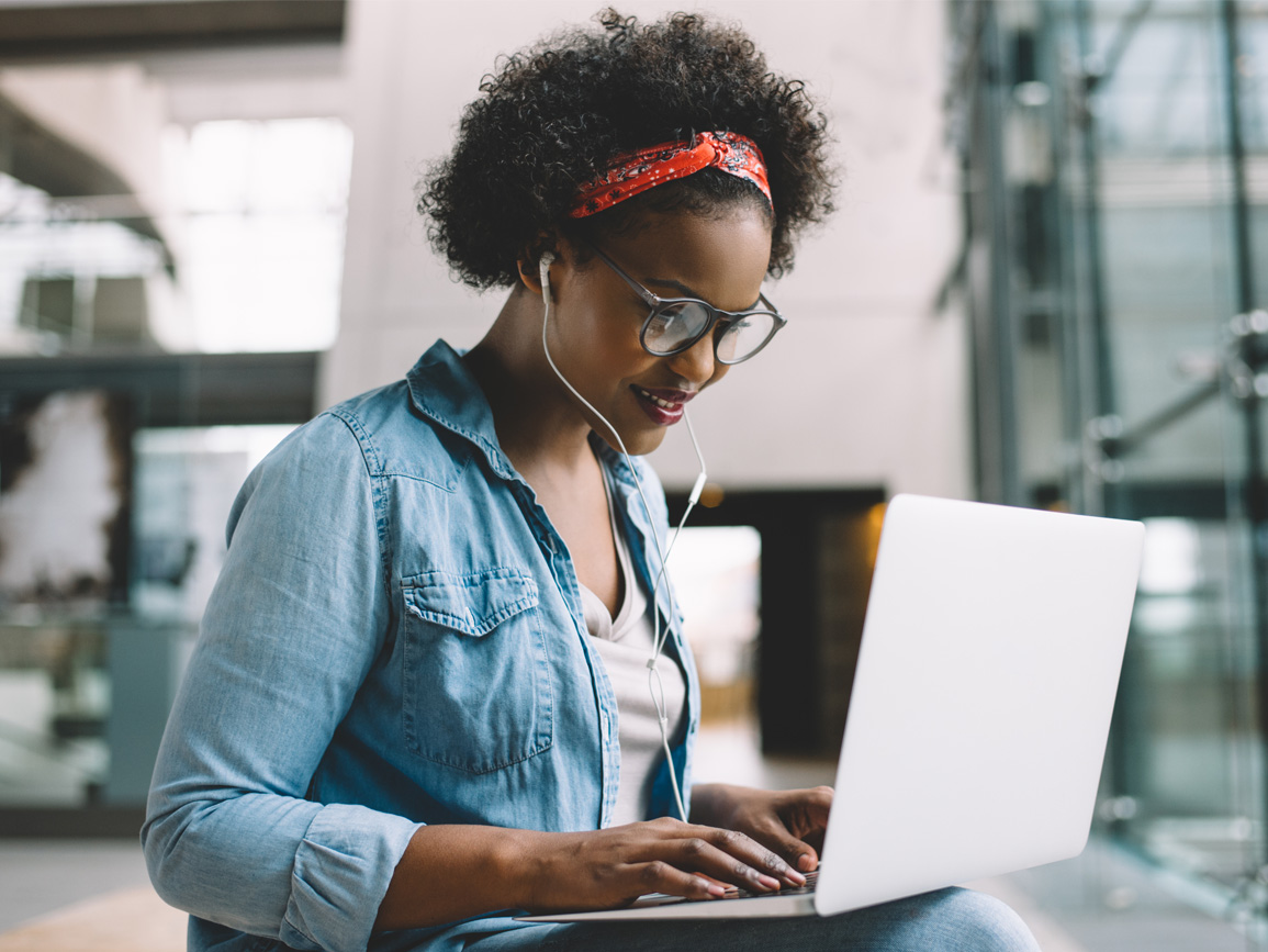 female on bench with laptop and headphones on learning 