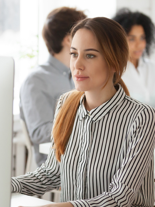 A woman on a computer while sitting at her desk