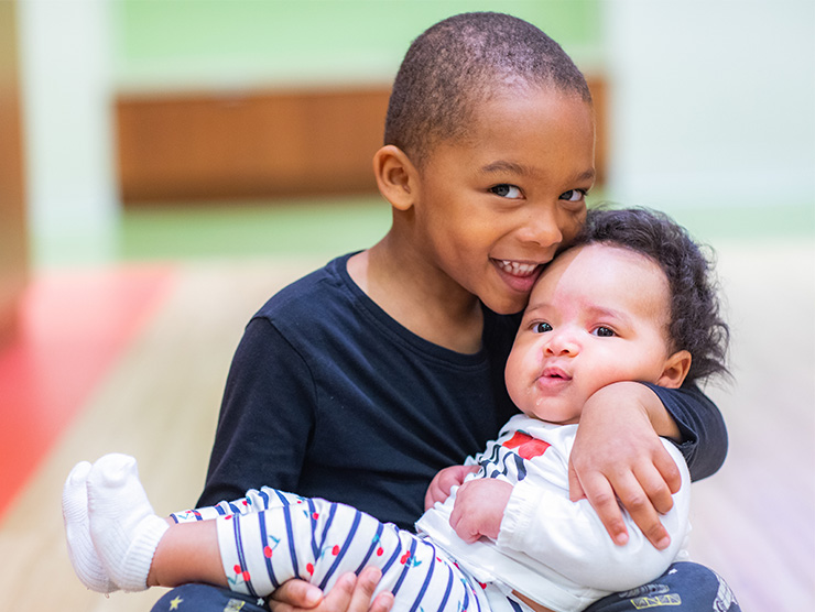 Child holding baby sibling