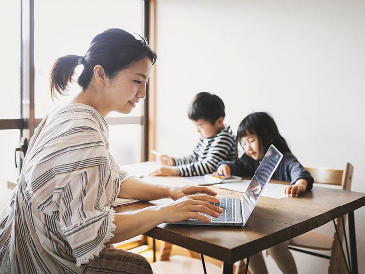 Mother working on laptap with her two kids at the dinner tables