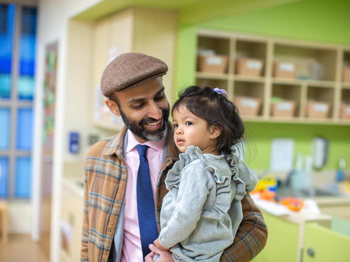 father picking up toddler daughter in childcare center