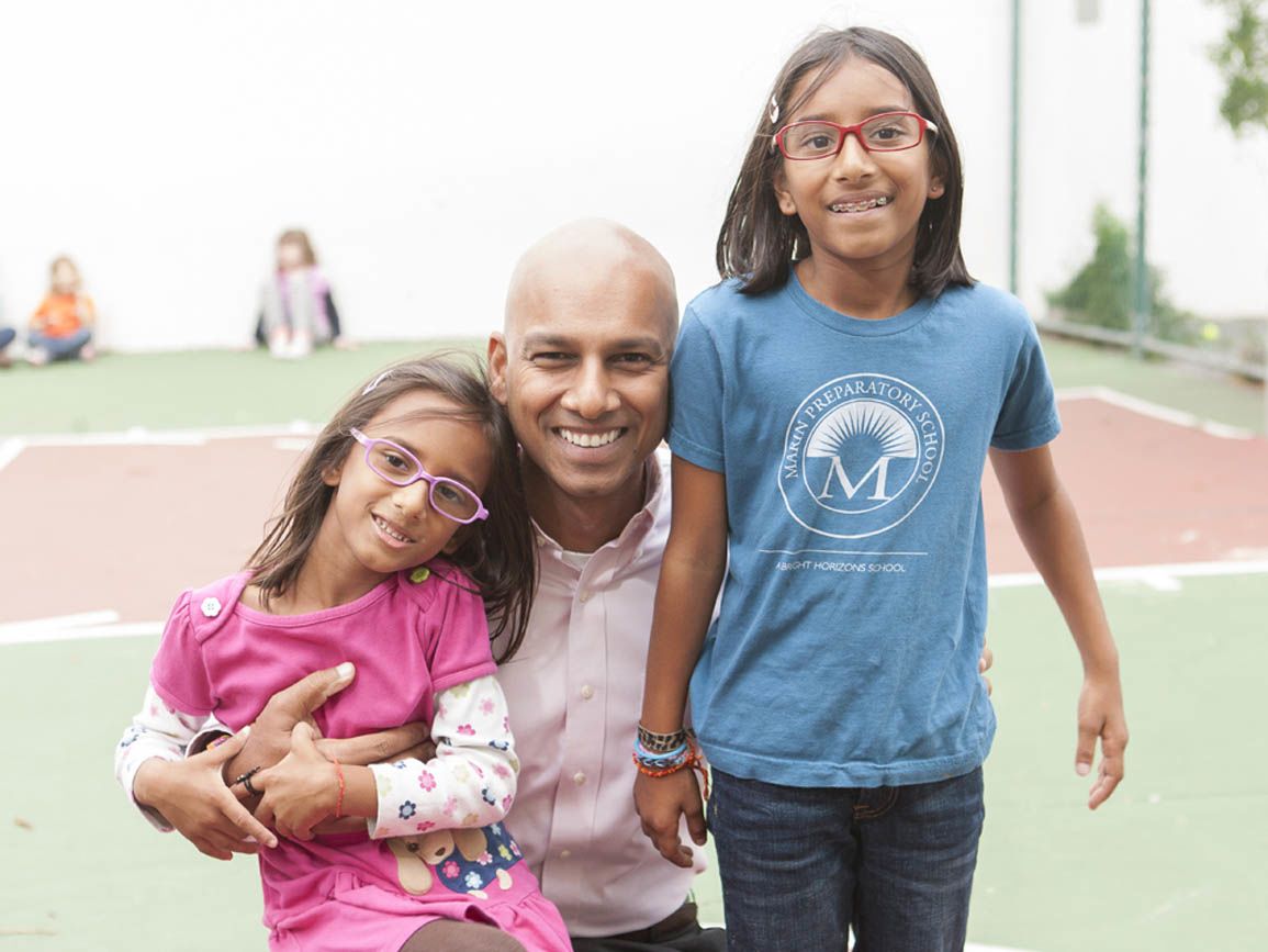 A father posing with his daughters on the playground