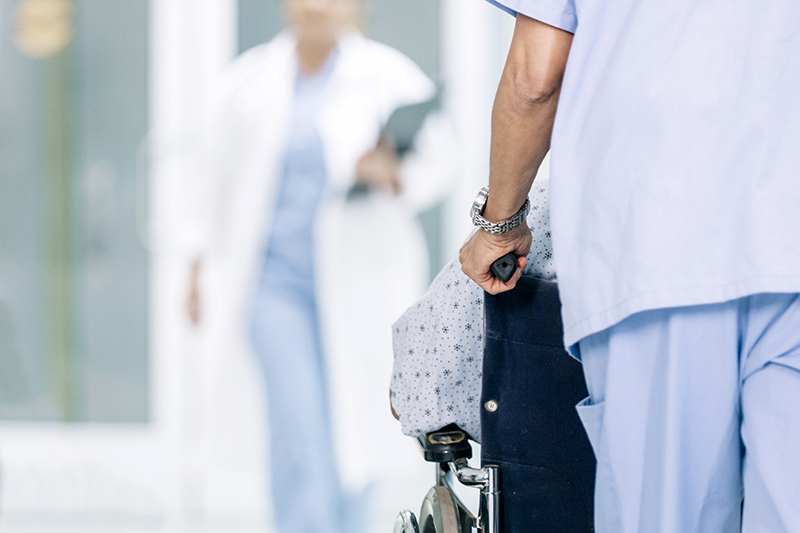 Allied Health professional wheeling a patient in a wheelchair