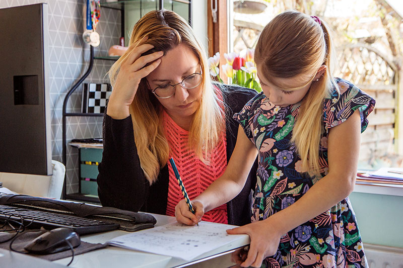 Mom trying to work and help her daughter with homework at home