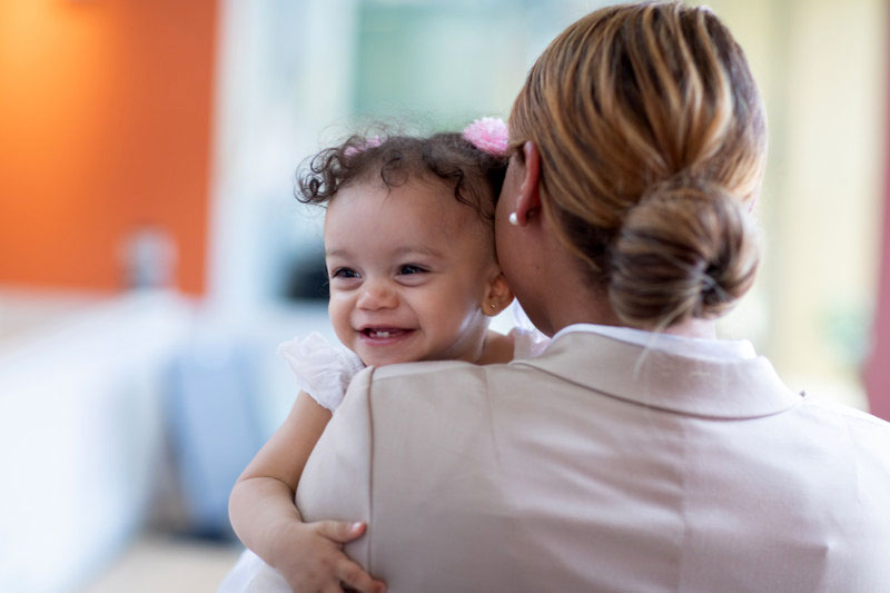 Working mom holding her toddler daughter