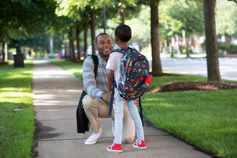 Working dad walking his son to school after summer vacation