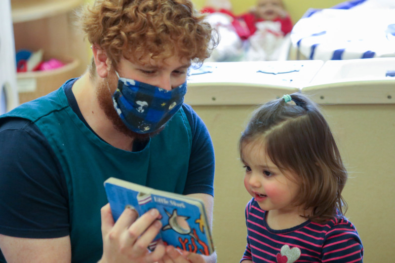 Teacher reading to preschooler in a reopened child care center