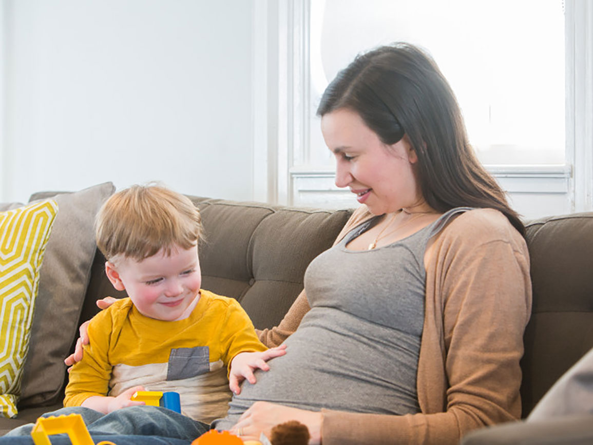 Preschool boy touching his mom's pregnant stomach