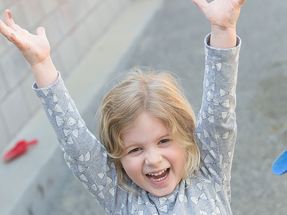 Preschool girl smiling with her hands in the air