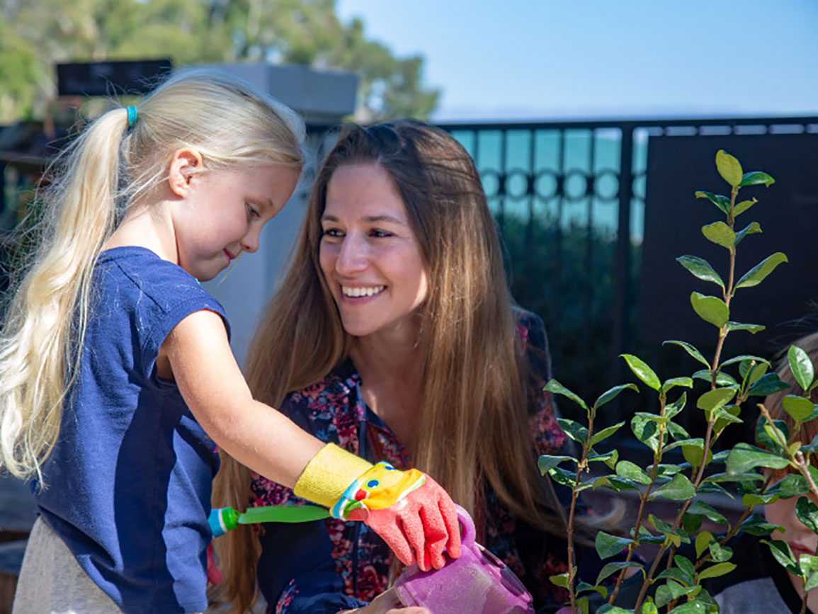 Mom and daughter watering plants together outside