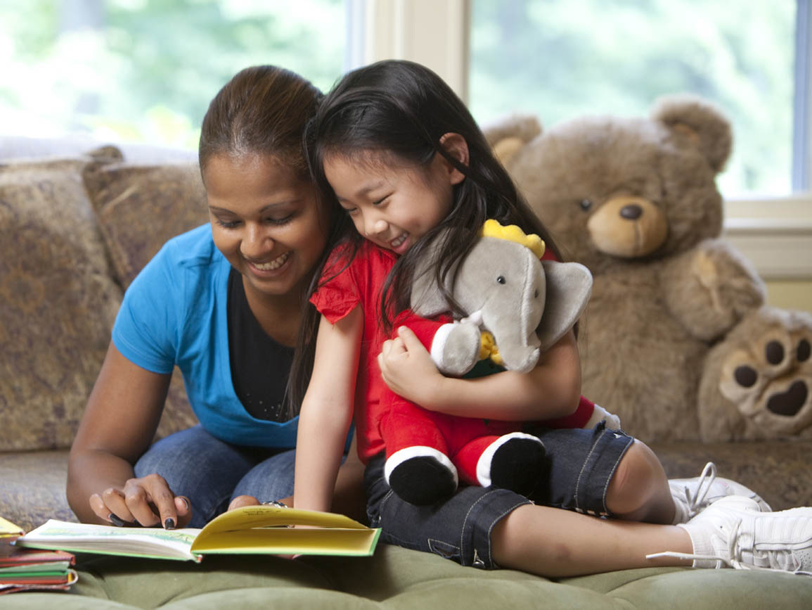 A little girl and a child care teacher reading together