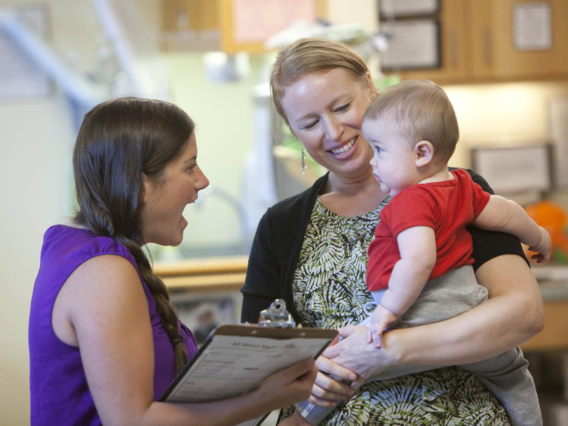 A mother and infant with their child care teacher