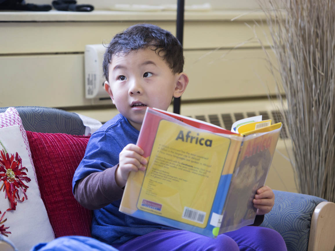 Preschool boy reading book about Africa