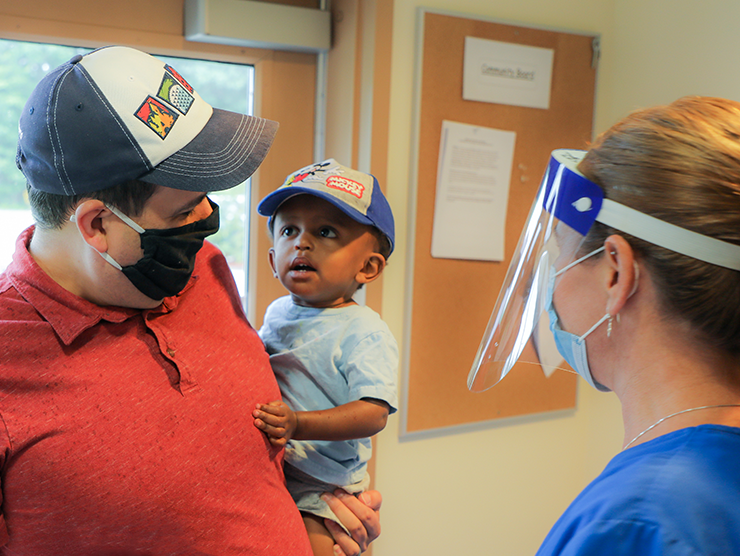 Parent holding child in bright horizons with masks on