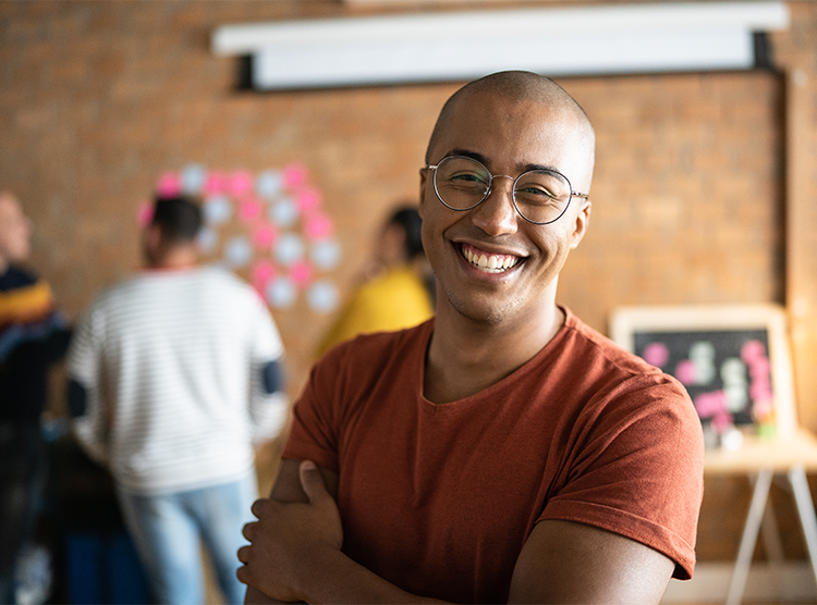 Man with glasses smiling as he's standing in his company office