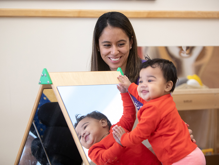 baby exploring identity using a mirror at daycare