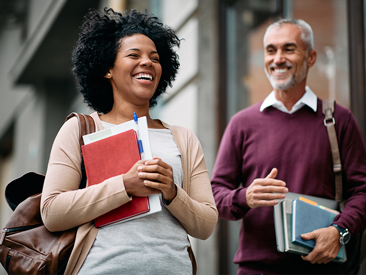 A female adult learner outside with a male adult learner, both smiling.